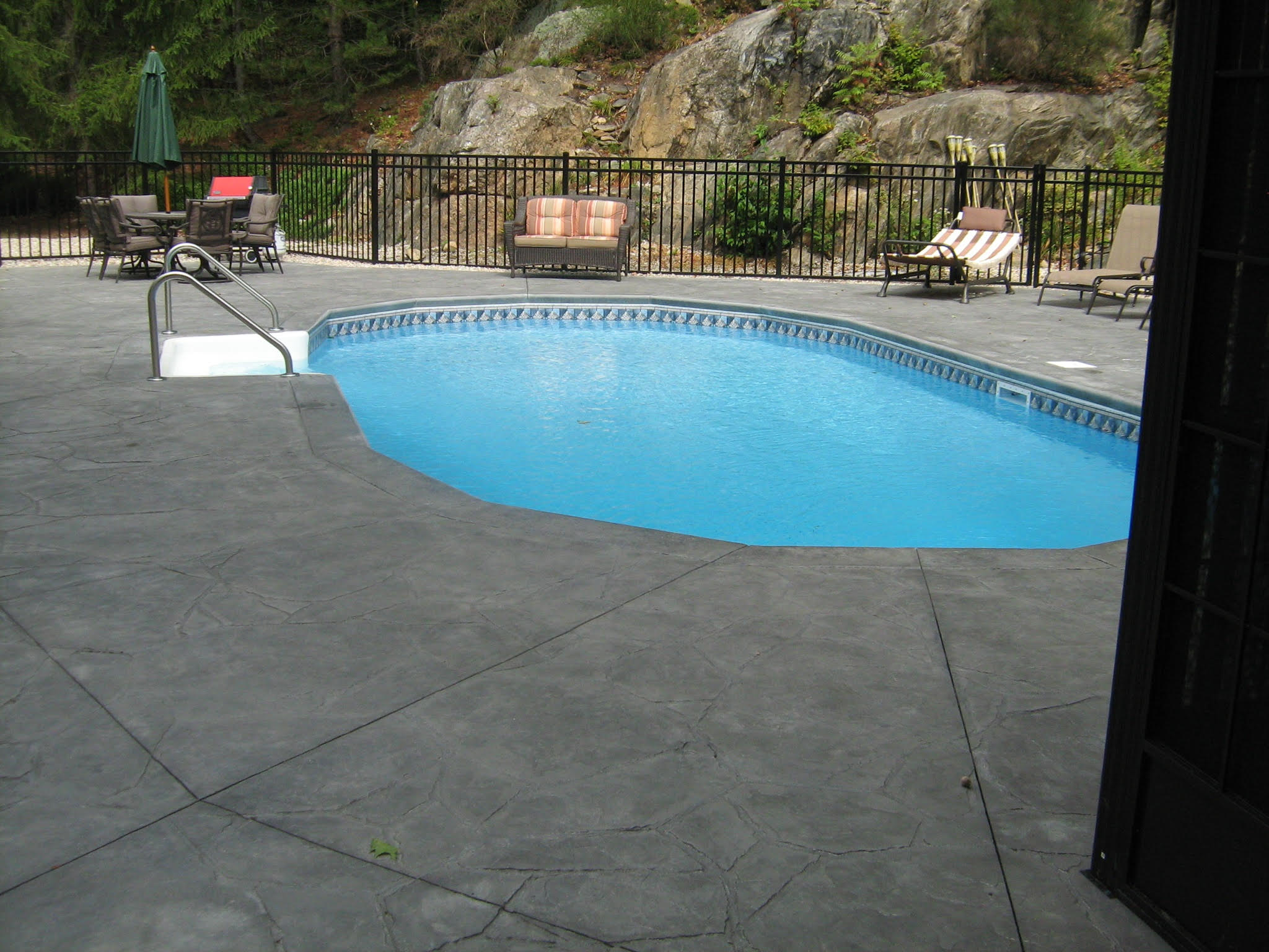 After pool setting with finished stamped concrete deck and updated backyard edges